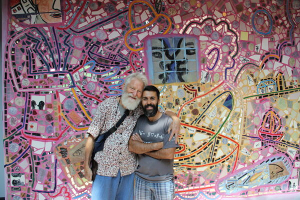 Isaiah Zagar and his former assistant Majid Iraei stand in front of a mosaicked wall.