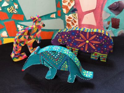 Three small wooden animals - a kangaroo, an aardvark, and a hippo - are adorned with bright colors and patterns
