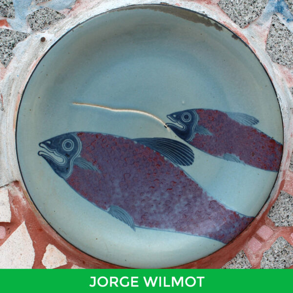 A large round ceramic disk with the image of two fish on it by Jorge Wilmot.