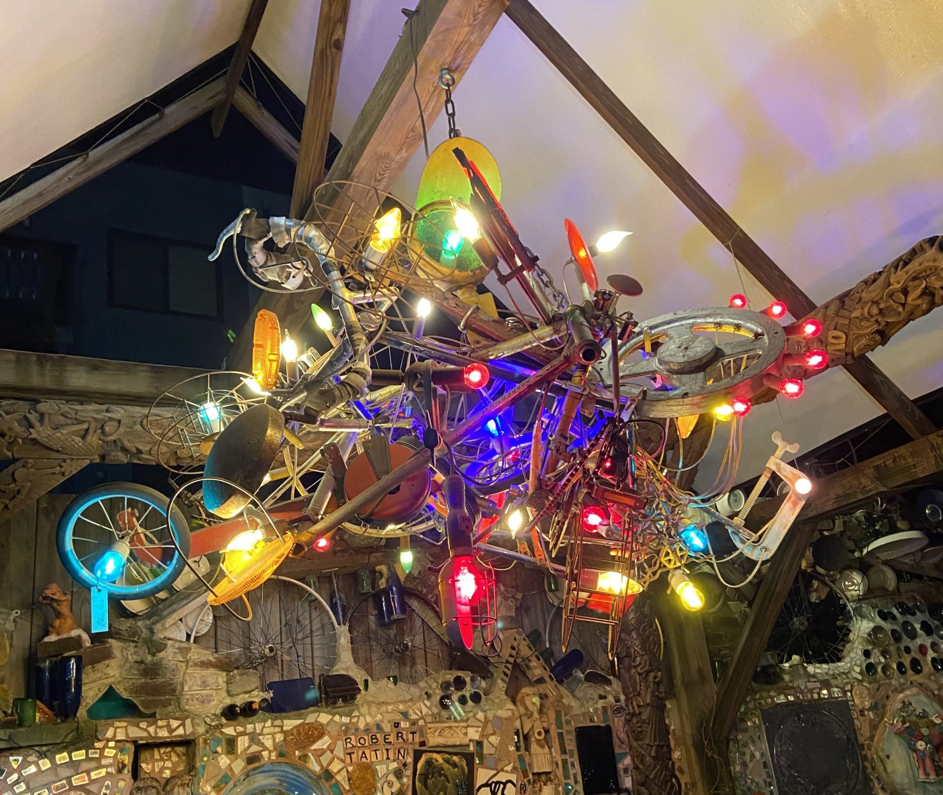 A chandelier made out of bicycle parts and colorful lightbulbs.