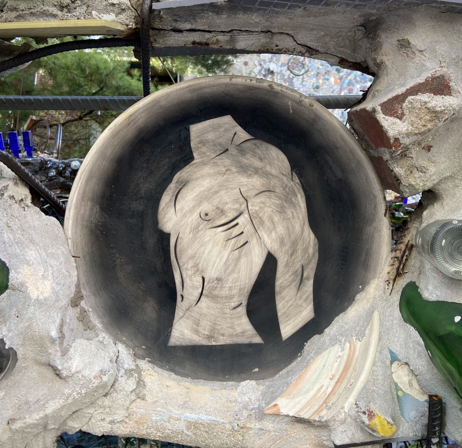 A ceramic plate with a man's torso painted on it.