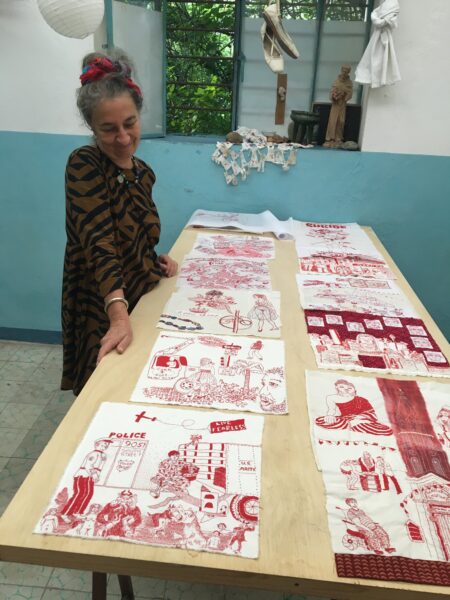 A former resident artist, Ornella Ridone, looks down at a table of her embroidery pieces.