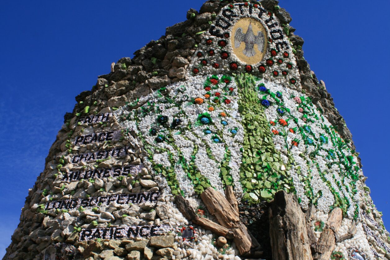 A round, stone structure with mosaicked elements on it. The words "peace, chastity, mildness, long suffering, and patience" can be seen on the side. At the top is the word "fortitude."