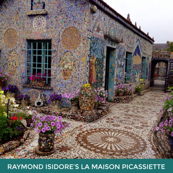 Raymond Isidore’s La Maison Picassiette. The exterior of a building completely covered in mosaics. Flowers and more mosaics are on the ground outside the building. 