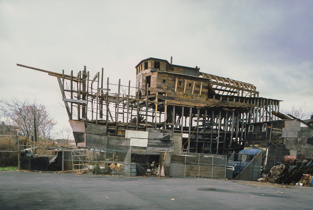 The framework of a large ark created from wood in an empty lot.