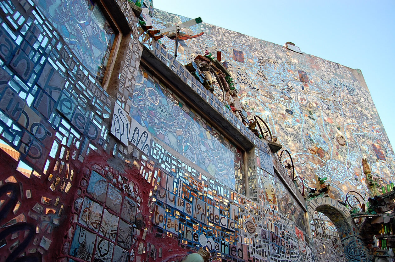 A mosaicked wall outside at Philadelphia's Magic Gardens with a stained glass window.