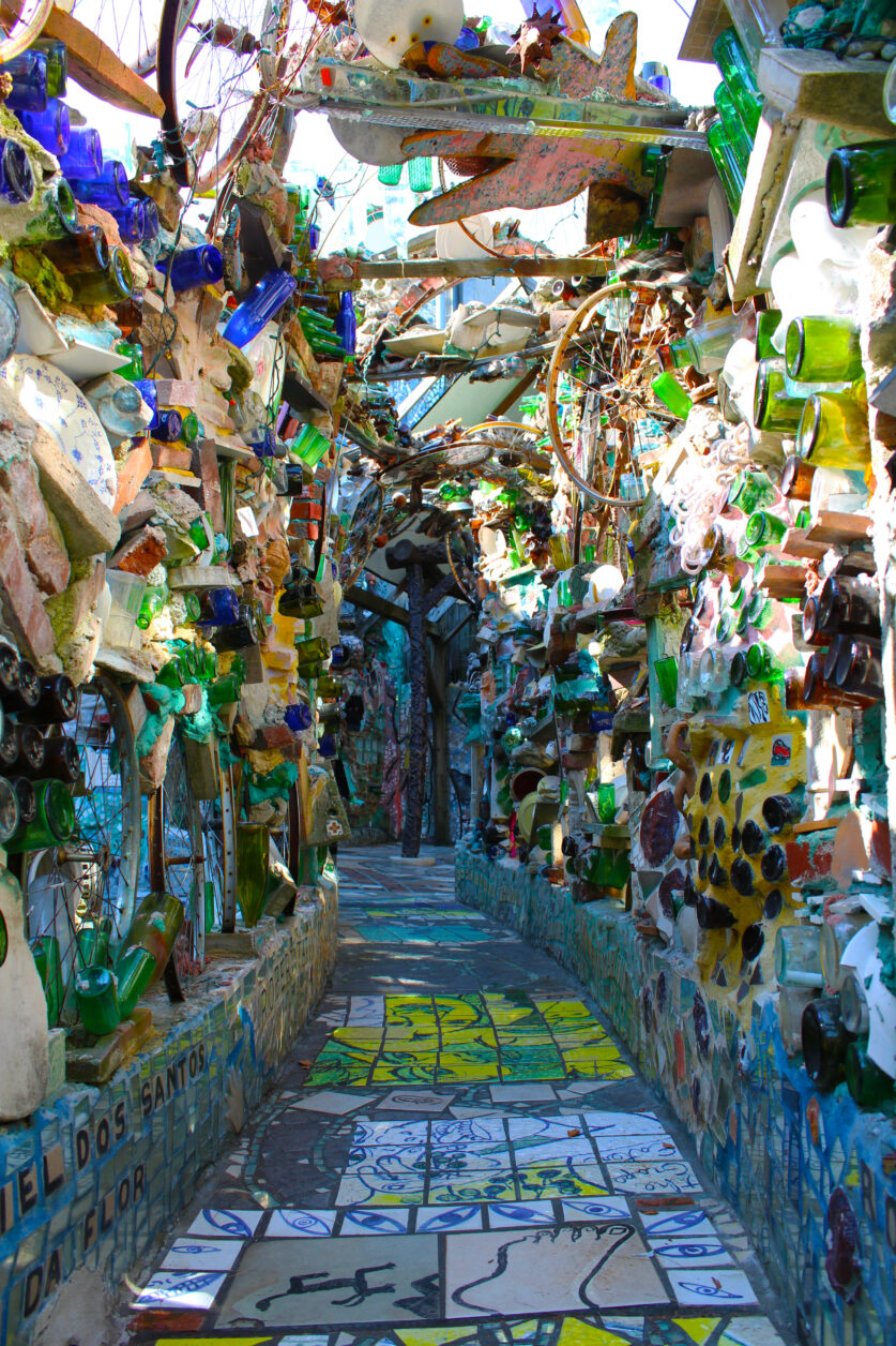 A hallway outside at Philadelphia's Magic Garden with a tunnel created with bottles, bike wheels, and other sculptural elements.