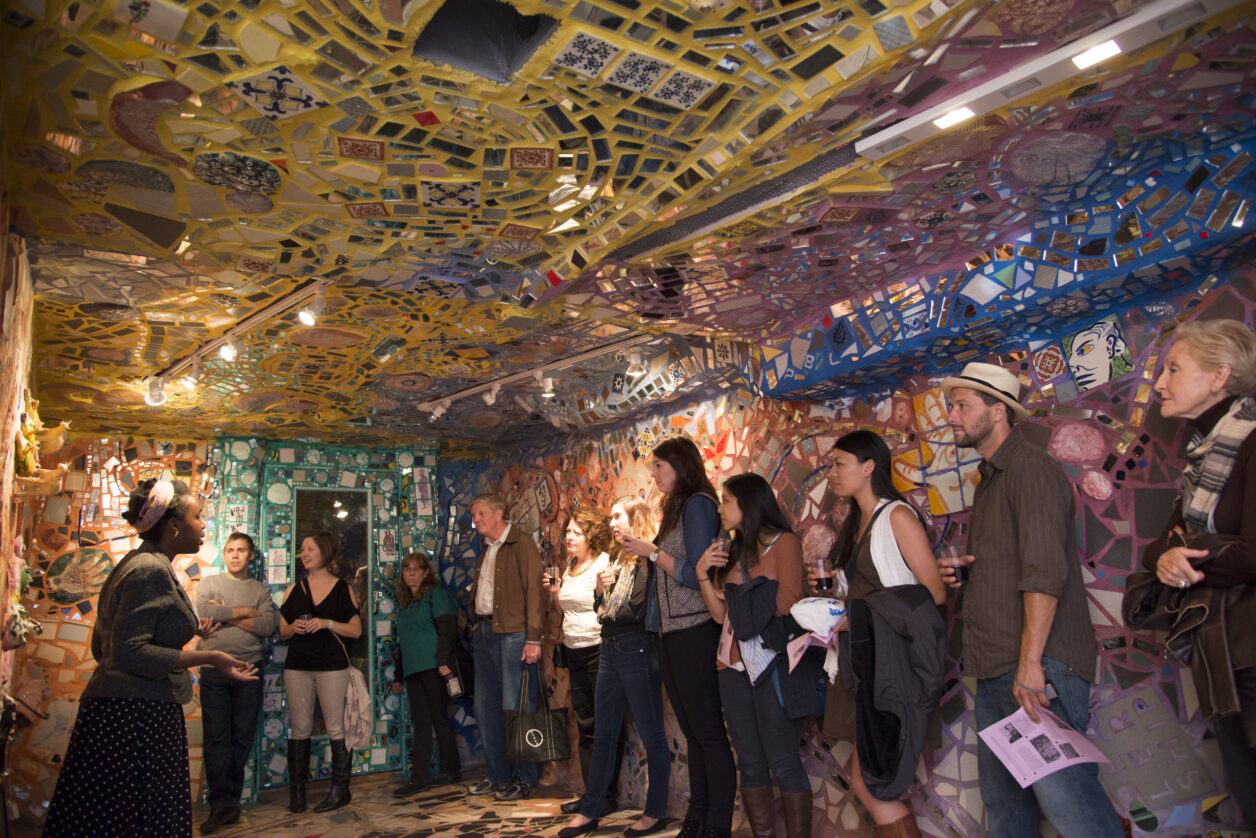 A group standing in the fully-mosaicked basement listening to a guide
