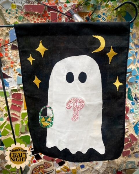 A black flag with a white ghost on it. The ghost has the Phillies symbol on its chest and gold stars around its head.