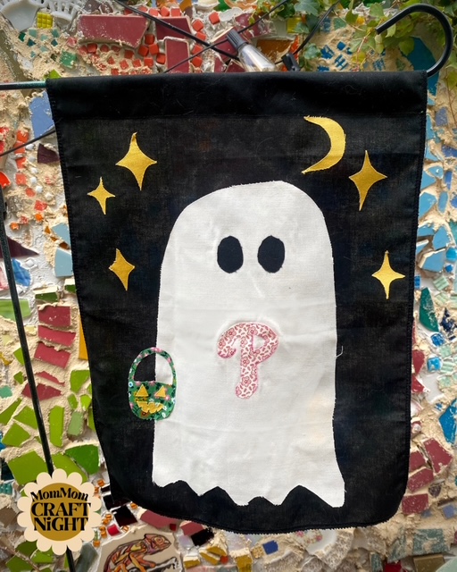 A black flag with a white ghost on it. The ghost has the Phillies symbol on its chest and gold stars around its head.